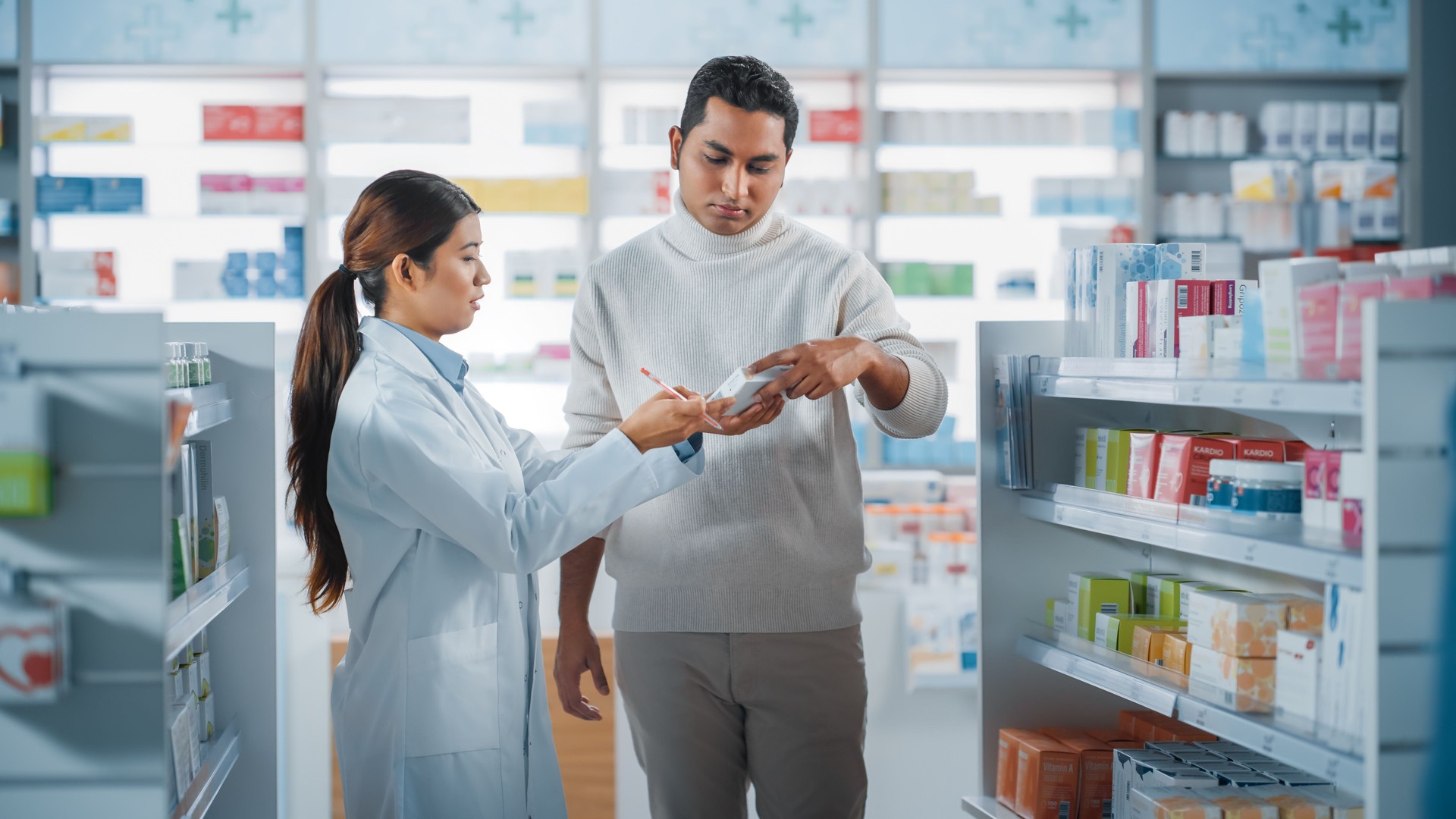 Farmacia Farmacia Farmacia: Farmacéutica Asiática Femenina Ayudando Al Cliente Masculino Indio con Recomendación, y Consejos para Comprar Medicamentos, Medicamentos, Vitaminas. Estantes modernos de tiendas farmacéuticas con productos de atención médi
